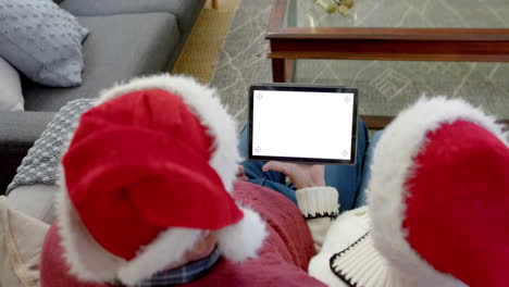 Senior-caucasian-couple-in-santa-hats-with-tablet-with-copy-space-at-christmas,-slow-motion