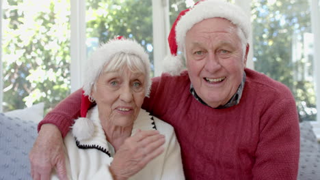 Senior-caucasian-couple-wearing-santa-hats-having-christmas-video-call,-slow-motion