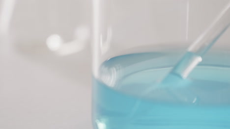 Video-Einer-Laborschale-Aus-Glas-Mit-Blauer-Flüssigkeit-Mit-Kopierraum-Auf-Weißem-Hintergrund