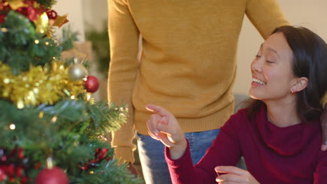 Glückliches,-Vielfältiges-Paar,-Das-Zu-Hause-Den-Weihnachtsbaum-Schmückt,-Zeitlupe
