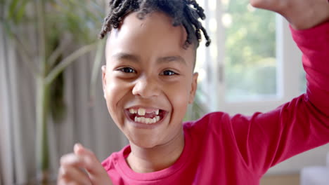 Portrait-of-happy-african-american-boy-with-missing-teeth-dancing-in-sunny-room,-slow-motion