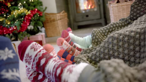 Moving-feet-of-family-in-warm-socks-by-fireplace-with-christmas-tree,-copy-space,-slow-motion