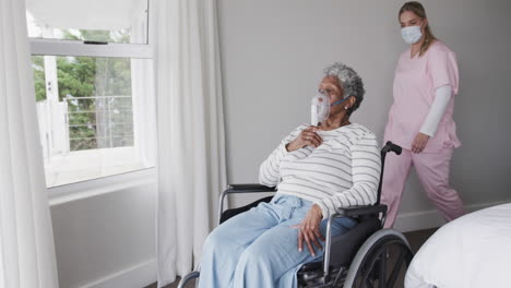 Caucasian-female-nurse-in-face-mask,-senior-african-american-woman-with-oxygen-mask,-slow-motion