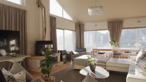 Panning-shot-of-furnished-lounge-and-dining-room-with-large-sunny-windows,-copy-space,-slow-motion