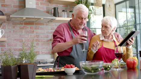 Älteres,-Kaukasisches-Paar-Kocht-Abendessen-Mit-Tablet-In-Der-Küche-Zu-Hause,-Zeitlupe
