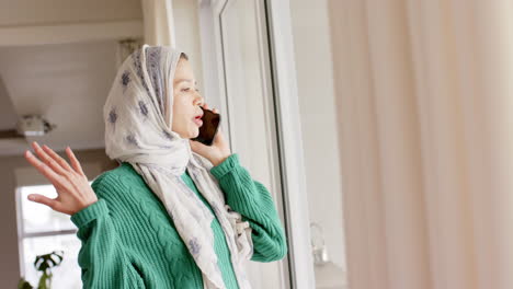 Mujer-Birracial-Con-Hijab-Usando-Un-Teléfono-Inteligente-En-Casa-Con-Espacio-Para-Copiar,-Cámara-Lenta