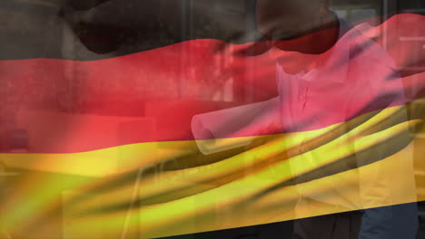 Animation-of-flag-of-germany-over-biracial-engineer-looking-at-floor-plan-on-blueprint