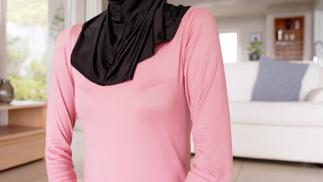 Focused-biracial-woman-in-hijab-practicing-yoga-at-home-with-copy-space,-slow-motion