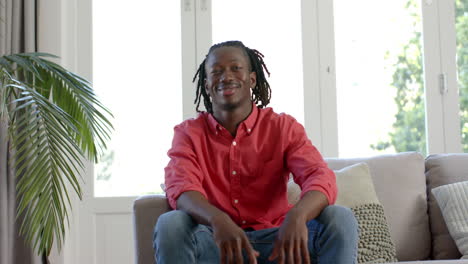 Happy-african-american-man-with-dreadlocks-having-video-call-in-sunny-living-room,-slow-motion