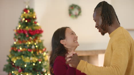 Glückliches,-Vielfältiges-Paar,-Das-Zu-Hause-Am-Weihnachtsbaum-Tanzt,-Zeitlupe