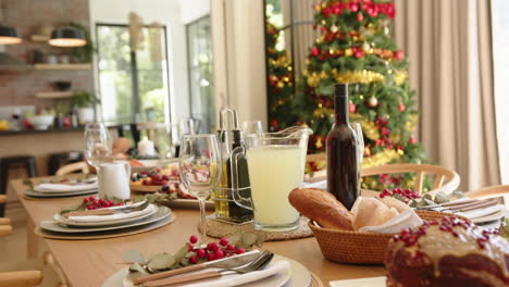 Dining-table-set-for-christmas-celebration-meal-with-tree-in-background,-slow-motion