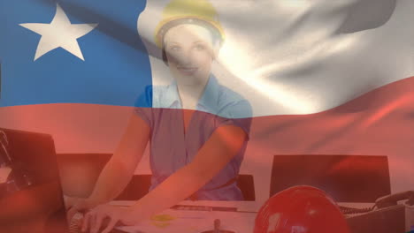 Animation-of-chile-flag-waving-over-caucasian-woman-wearing-yellow-helmet-using-computer