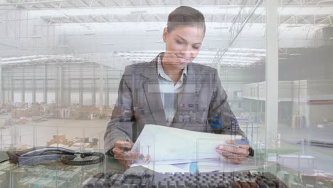 Animation-of-aerial-view-of-warehouse,-biracial-businesswoman-analyzing-reports-and-using-computer