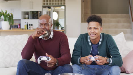 Excited-african-american-father-and-adult-son-playing-video-game-and-celebrating,-slow-motion