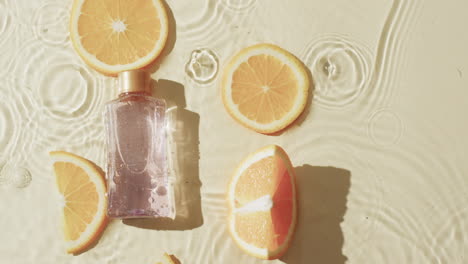 Video-Einer-Kosmetikflasche-Und-Orangenscheiben-Im-Wasser-Mit-Kopierraum-Auf-Gelbem-Hintergrund