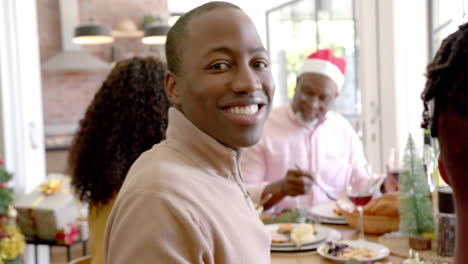 Happy-african-american-father-smiling-at-multi-generation-family-christmas-dinner-table