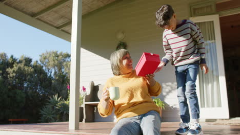 Happy-senior-biracial-grandmother-and-grandson-giving-presents-on-terrace,-slow-motion,-copy-space