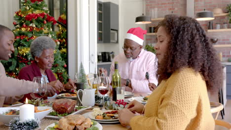 Happy-african-american-mother-smiling-at-multi-generation-family-christmas-dinner-table