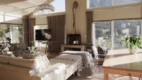 Panning-shot-of-furnished-living-room-home-interior-with-view-to-mountainside,-slow-motion