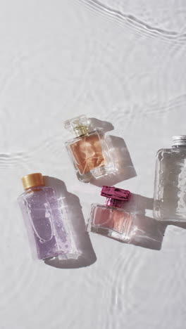 Vertical-video-of-beauty-product-bottles-in-water-with-copy-space-on-white-background