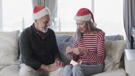 Middle-aged-caucasian-couple-in-santa-hats-talking-at-christmas-at-home,-slow-motion