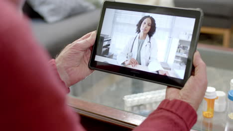 Senior-caucasian-man-using-tablet-for-online-consultation-with-biracial-female-doctor,-slow-motion
