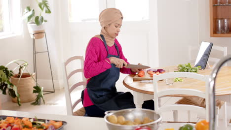 Mujer-Birracial-Con-Hijab-Lavando-Comida-En-La-Mesa-En-Casa-Con-Espacio-Para-Copiar,-Cámara-Lenta
