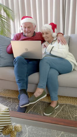 Vertikales-Video-Eines-älteren-Kaukasischen-Paares,-Das-Einen-Laptop-Für-Einen-Weihnachtsvideoanruf-Verwendet,-Zeitlupe