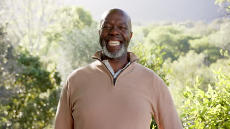 Portrait-of-happy-senior-bald-african-american-man-smiling-in-sunny-nature,-slow-motion