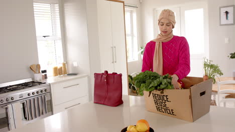 Biracial-Frau-Im-Hijab-Beim-Lebensmitteleinkauf-In-Der-Küche-Zu-Hause-Mit-Kopierraum,-Zeitlupe