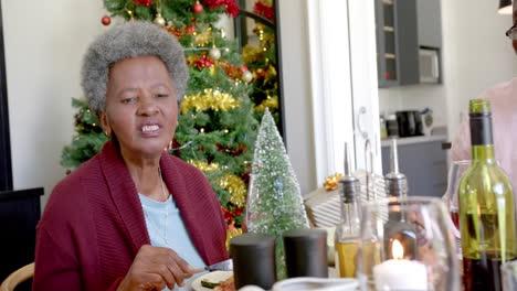 Glückliche-Afroamerikanische-Großmutter-Im-Gespräch-Am-Weihnachtstisch-Einer-Mehrgenerationenfamilie