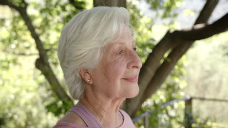Portrait-of-happy-senior-caucasian-woman-with-white-hair-in-sunny-nature,-copy-space,-slow-motion