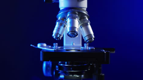 Video-of-close-up-of-laboratory-microscope-with-copy-space-on-blue-background