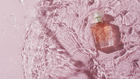 Video-of-beauty-product-bottle-in-water-with-copy-space-on-pink-background
