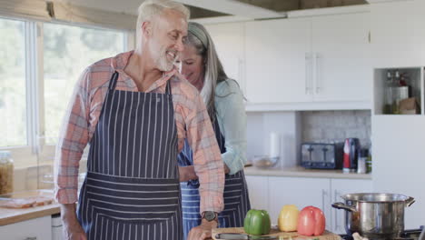 Middle-aged-caucasian-couple-putting-apron,-cooking-in-kitchen-at-home,-slow-motion