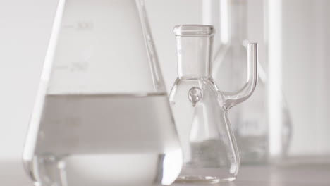 Video-of-close-up-of-glass-laboratory-beakers-and-dishes-with-copy-space-on-white-background