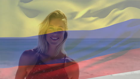 Animation-of-colombian-flag-over-smiling-caucasian-woman-standing-against-sea-at-beach