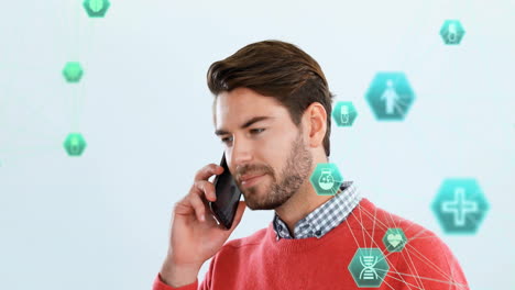 Animation-of-connected-icons-globe-over-caucasian-man-standing-and-talking-on-smartphone