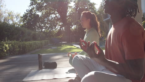 Happy-diverse-couple-practicing-yoga-meditation-sitting-out-in-sun,-copy-space,-slow-motion