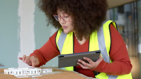 Casual-biracial-female-architect-with-tablet-looking-at-3d-model-in-office,-slow-motion,-copy-space