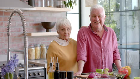 Portrait-of-happy-senior-caucasian-couple-cooking-dinner-in-kitchen-at-home,-slow-motion