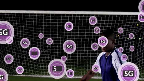 Animation-Eines-5G-Textes-In-Kreisen-über-Einem-Afroamerikanischen-Fußballspieler,-Der-Den-Ball-Gegen-Den-Torpfosten-Stoppt