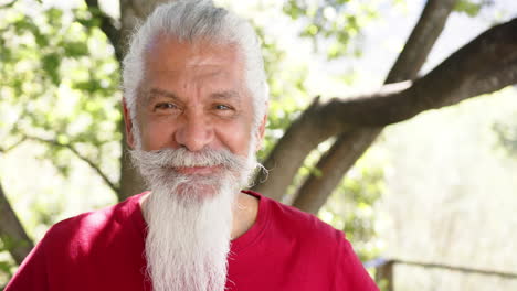 Portrait-of-happy-senior-biracial-man-with-white-beard-in-sunny-nature,-copy-space,-slow-motion