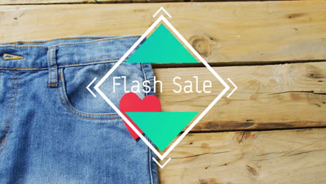 Animation-of-flash-sale-text-over-denim-trousers-on-wooden-background