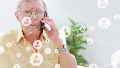 Animation-of-icons-connected-with-lines-over-senior-caucasian-man-talking-on-cellphone-at-home