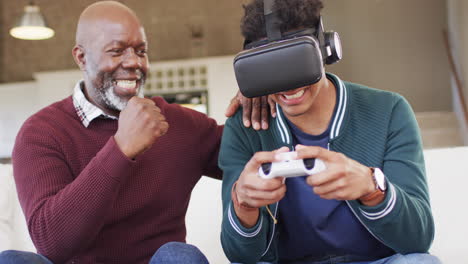 Happy-african-american-son-using-vr-headset-and-gamepad-with-senior-father-at-home,-slow-motion
