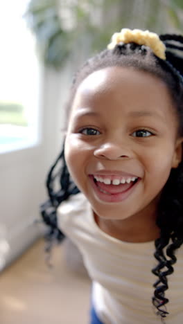 Vertical-video-portrait-of-happy-african-american-girl-with-braided-hair-smiling,-slow-motion