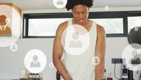 Animation-of-multiple-profile-icons-over-african-american-athlete-cutting-fruit-in-kitchen-at-home