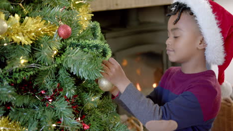 Feliz-Niño-Afroamericano-Con-Sombrero-De-Navidad-Decorando-El-árbol-De-Navidad,-Cámara-Lenta