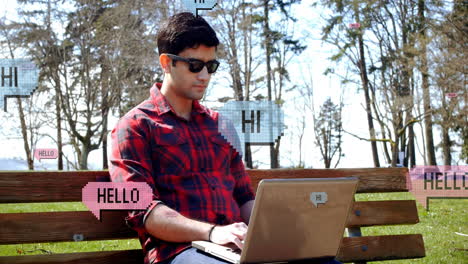 Animation-of-hi-and-hello-texts-in-speech-bubbles,-caucasian-man-working-on-laptop-in-outdoors